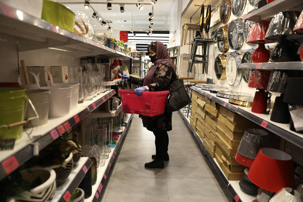 A woman wearing a face mask shops at a store in Bamland shopping mall, in Western Tehran, Iran, ...