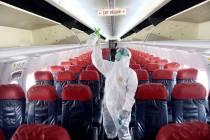 A worker sprays disinfectant inside the cabin of a Lion Air passenger jet as a precaution again ...