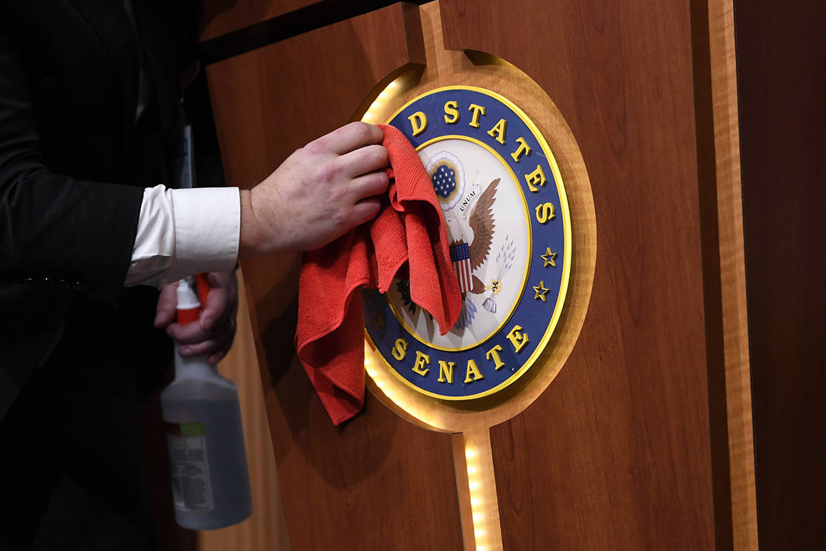 Mike Mastrian, Director of the Senate Radio and Television Gallery, cleans down the podium befo ...