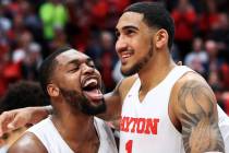 Dayton's Trey Landers, left, reacts with Obi Toppin, middle, as he celebrates scoring his 1,000 ...