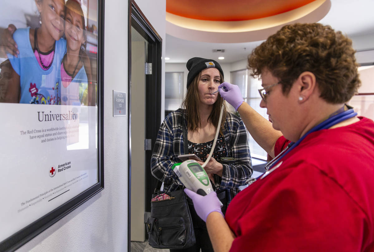 Blood donor Susan Hankin, left, has her temperature taken by Red Cross team leader Eva Klappa a ...