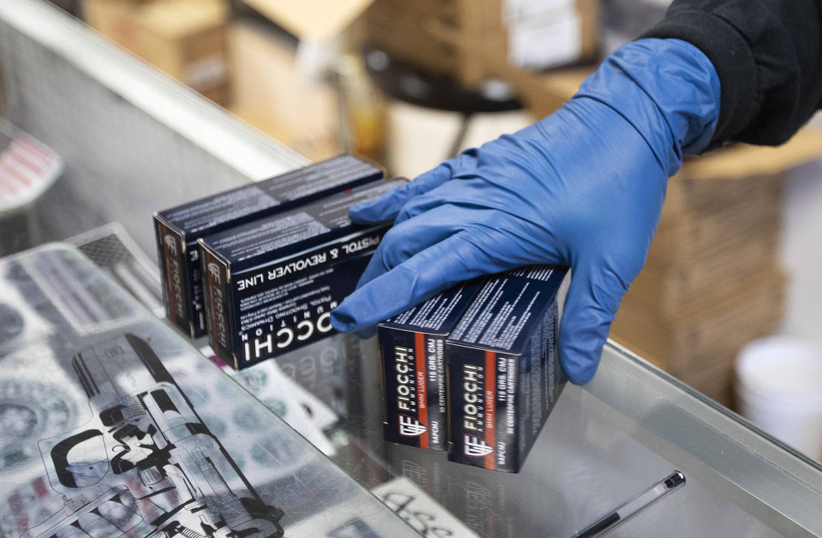 An employee at 2nd Amendment Gun Shop uses gloves while bagging ammunition for a customer on Tu ...