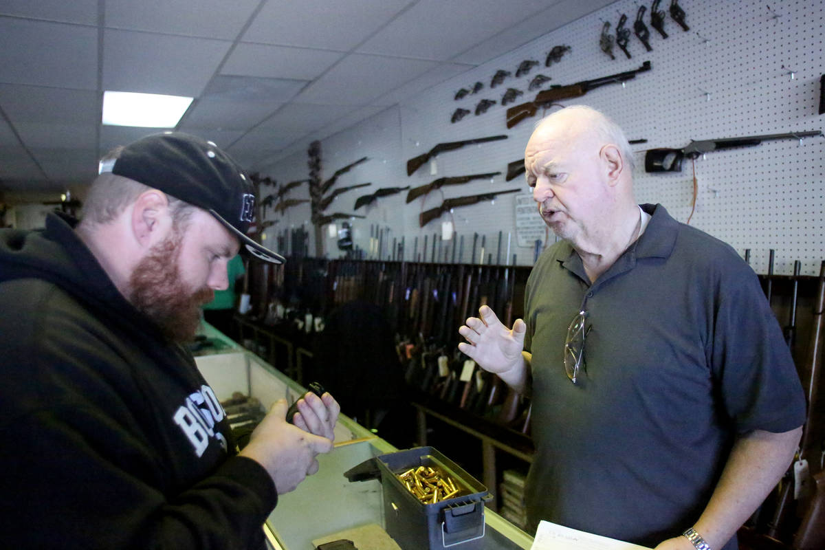 John Taylor, right, store manager of Elite Firearms assists customer Branden Miller on Tuesday, ...