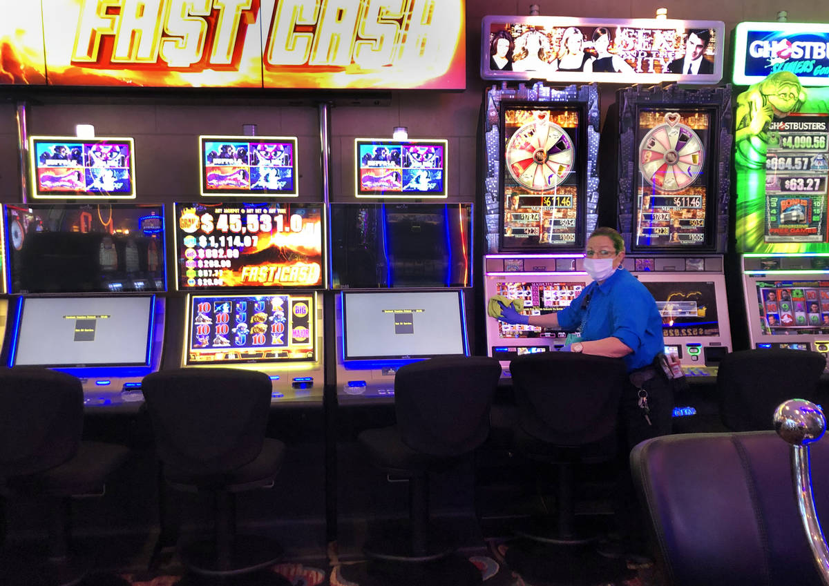 An employee at the Four Queens sanitizes the slots machines on Tuesday, March 17, 2020 in Las V ...