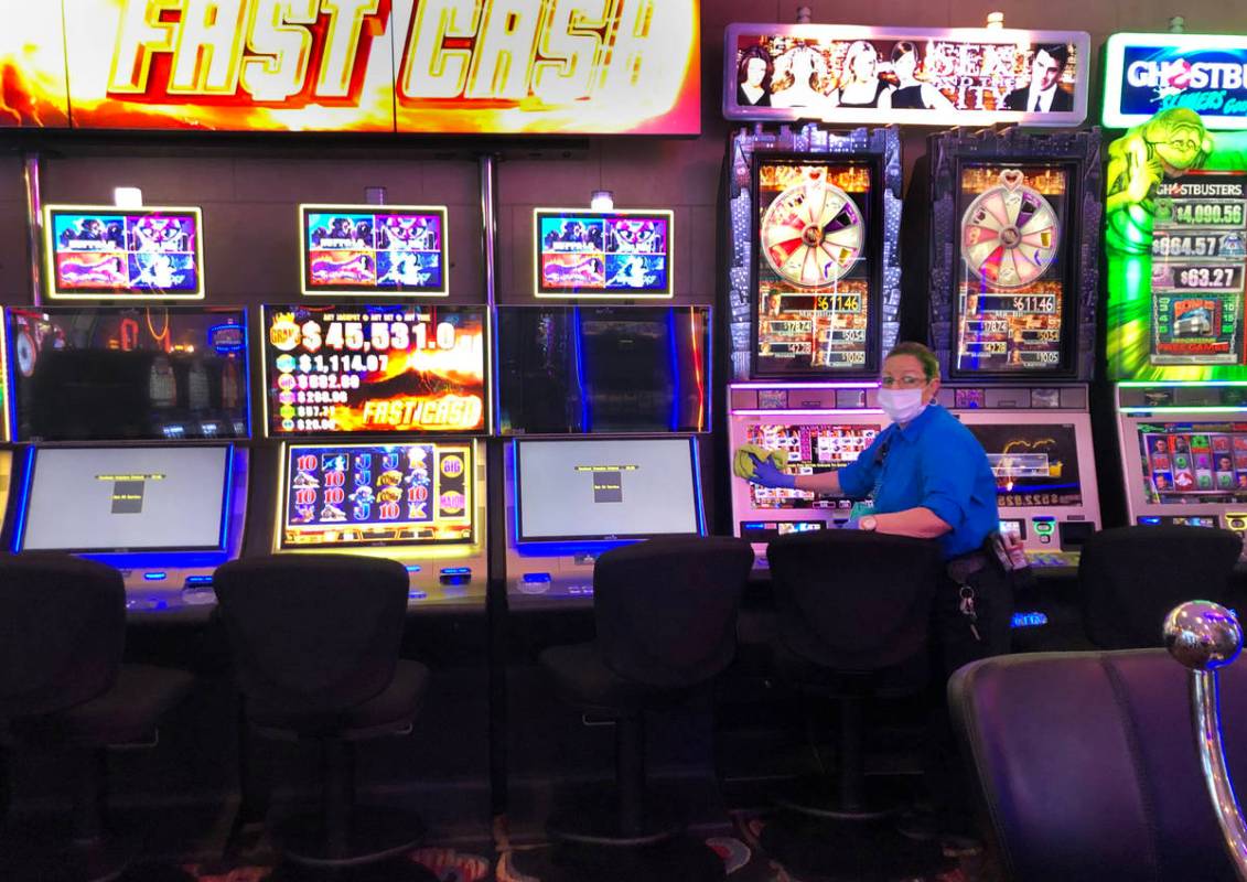 An employee at the Four Queens sanitizes the slots machines on Tuesday, March 17, 2020 in Las V ...