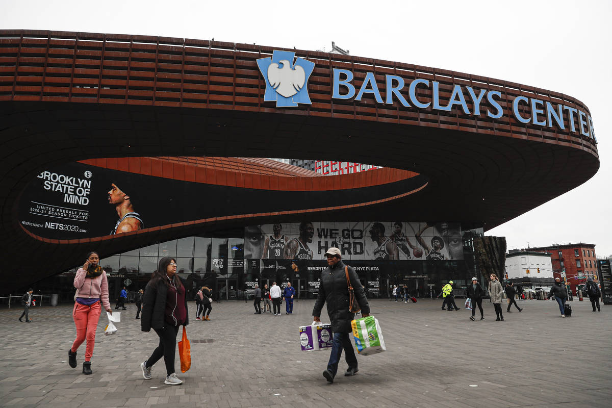 FILE - In this March 12, 2020, file photo, pedestrians walk past the Barclays Center, which is ...