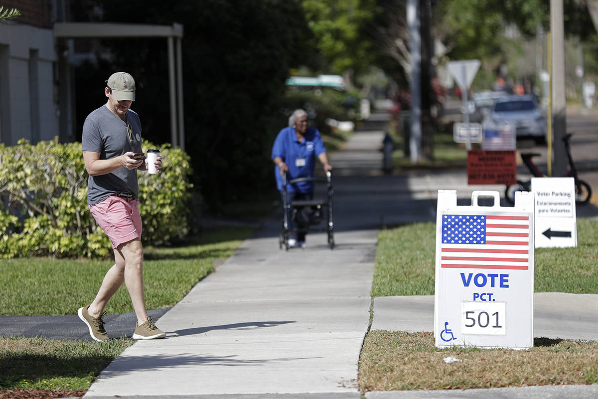 A voter, left, leaves a polling station after voting in Florida's primary election, Tuesday, Ma ...