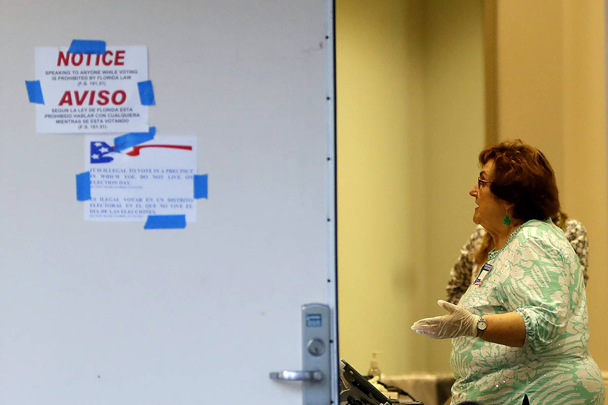 A polling place worker uses gloves at the Boca Raton Library during the Florida primary electio ...