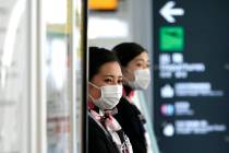 Airlines ground crews with protective masks to protect against the coronavirus stand at a check ...