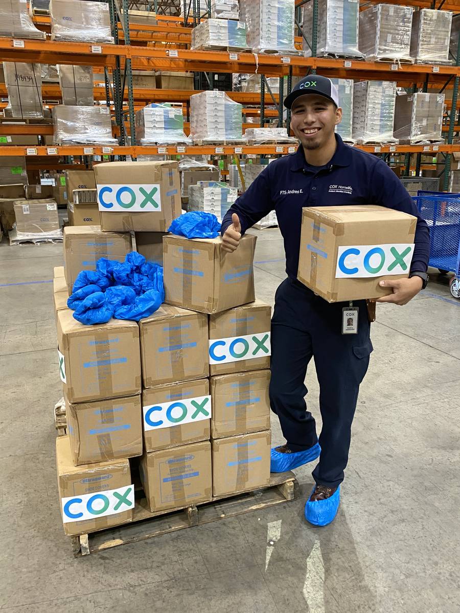 Cox Field Technician Andres Enriquez prepares boxes of protective shoe covers for UMC in one of ...