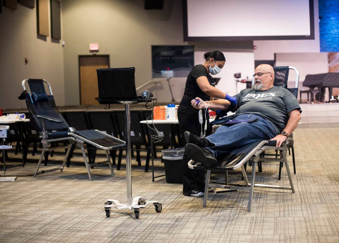 Shae Stanley, a phlebotomist tech, helps Scott Shaw prepare to give blood at a blood drive host ...