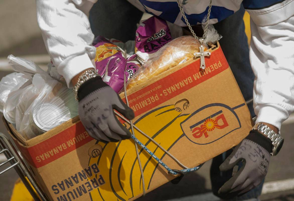 An individual straps an emergency food box to his bike at Lutheran Social Services of Nevada, i ...