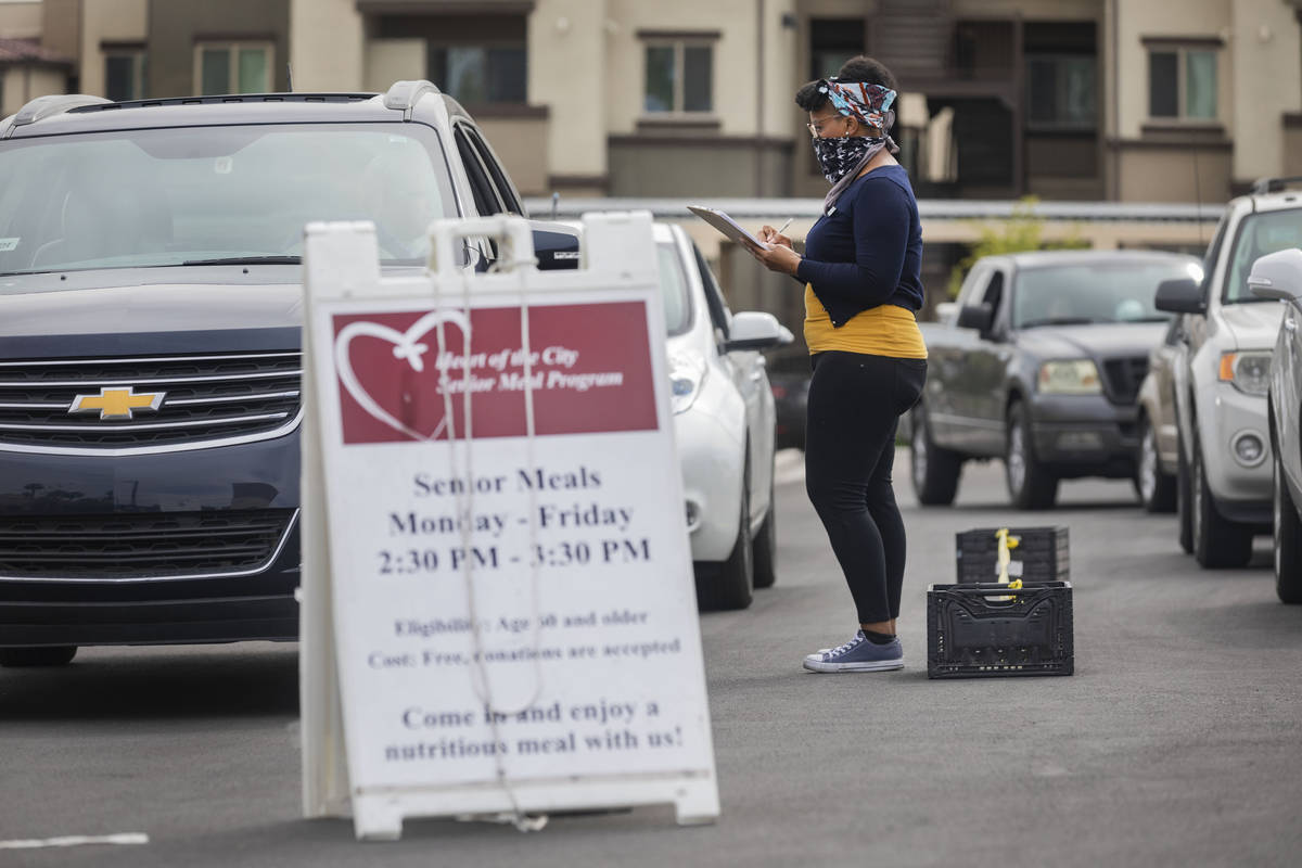 Community health worker for Lutheran Social Services of Nevada A.J. Tullos, greet a vehicle in ...