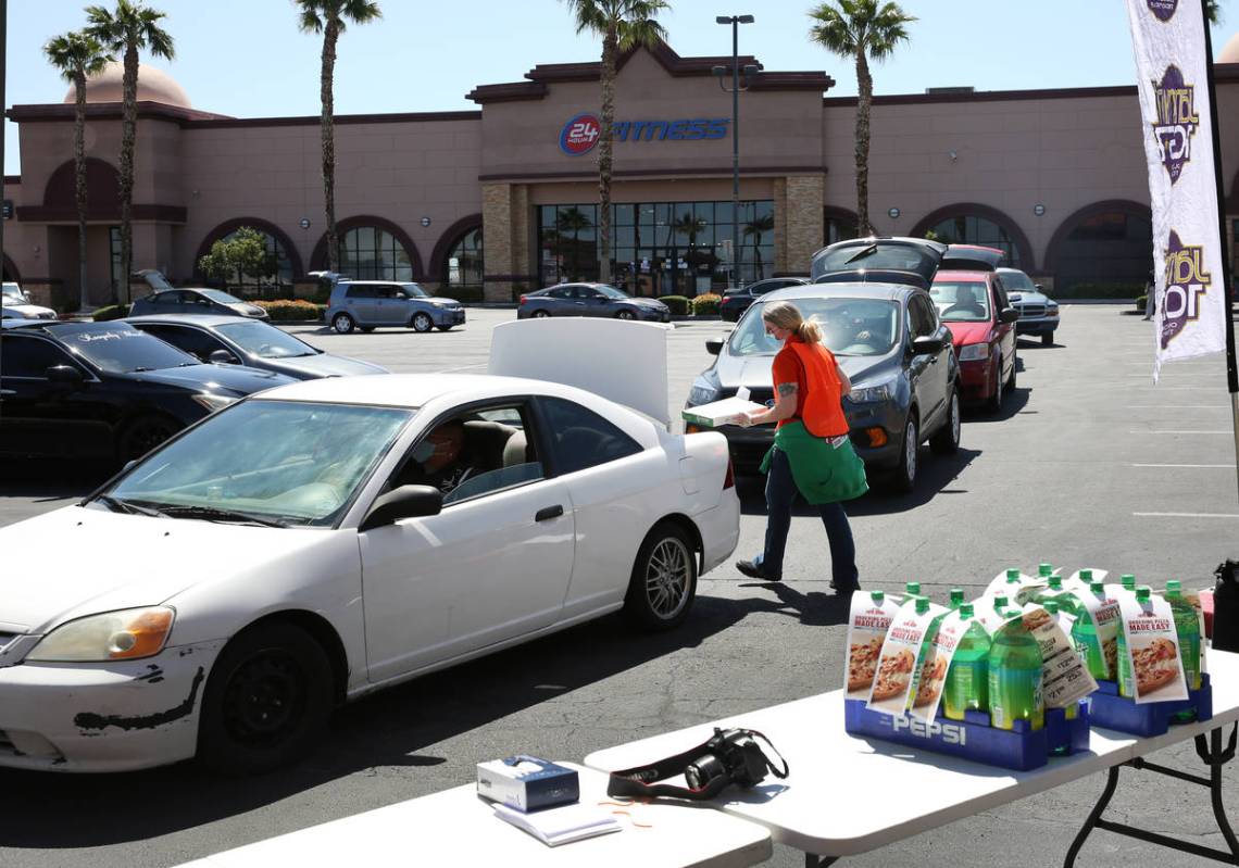 Katey Powell, district manager at Papa Jone's Pizza Las Vegas, places a box of pizza and a soft ...