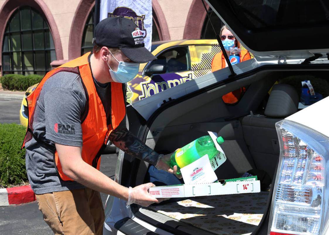 Mathew Christman, manager at Papa Jone's Pizza, places a box of pizza and a soft drink in a cli ...