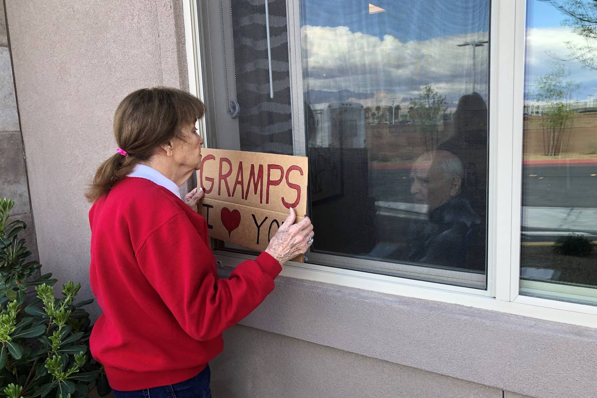Judy and Jan Swanson visit their family member, Mel Swanson, outside his window at his assisted ...