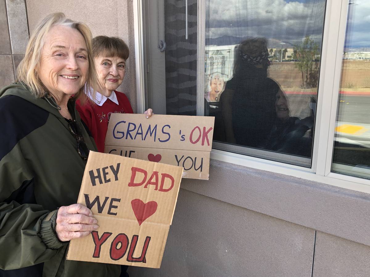 Judy and Jan Swanson visit their family member, Mel Swanson, outside his window at his assisted ...