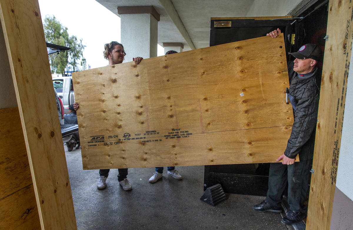 Cooper Cooley, left, and Anthony Dishari bring in plywood to help shore up the back door as the ...