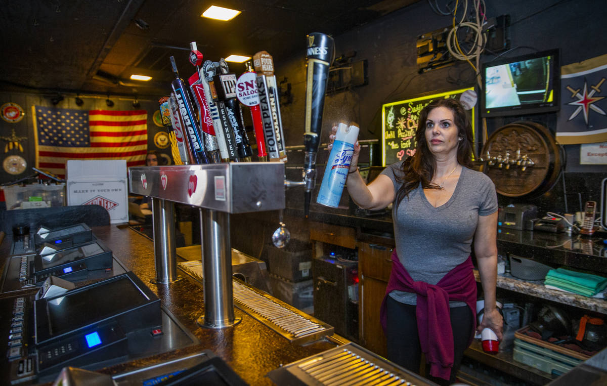 Saddle 'N' Spurs Saloon owner Melissa Kingston sanitizes bar taps as she and husband Bobby clo ...