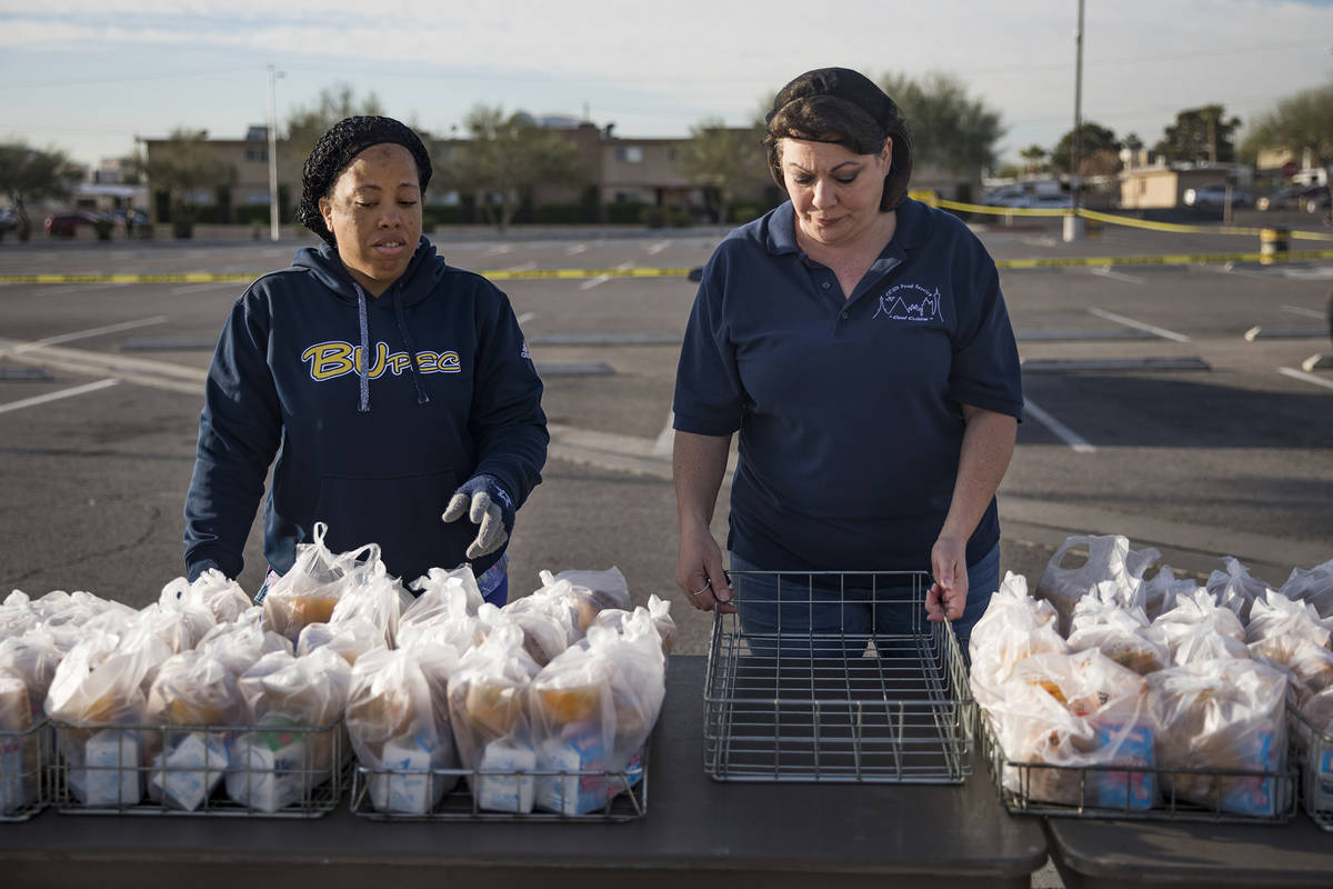 Clark County School District employees wait for families to pick up food at Clark High School i ...