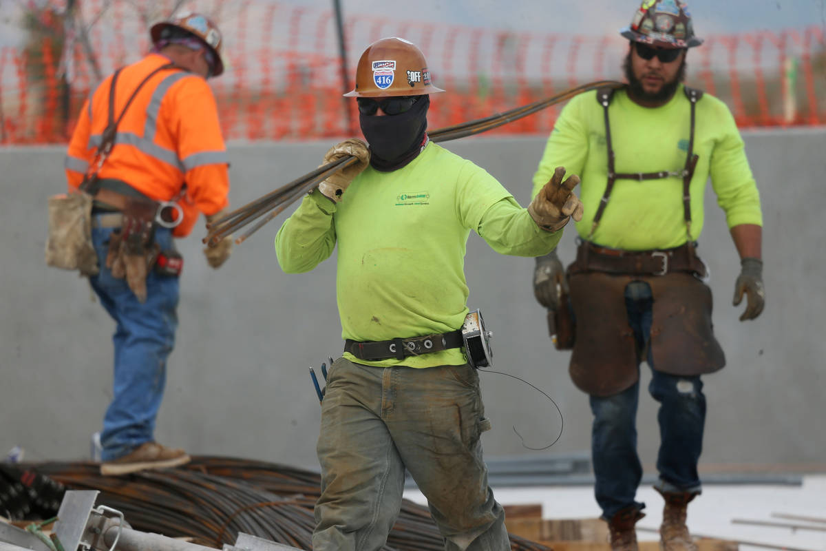 Workers carry rebar steel at the Raiders Allegiant Stadium construction site in Las Vegas, Wedn ...