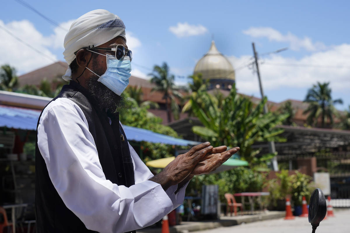 In this Monday, March 16, 2020, photo, a Muslim man wearing face masks wipes hands with hand-sa ...