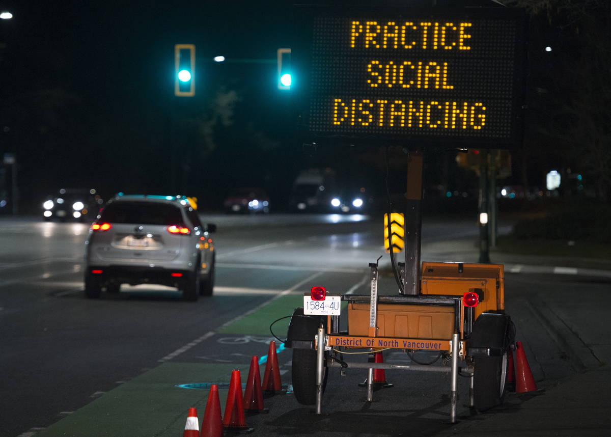 A sign reminding people about social distancing because of the coronavirus outbreak stands next ...