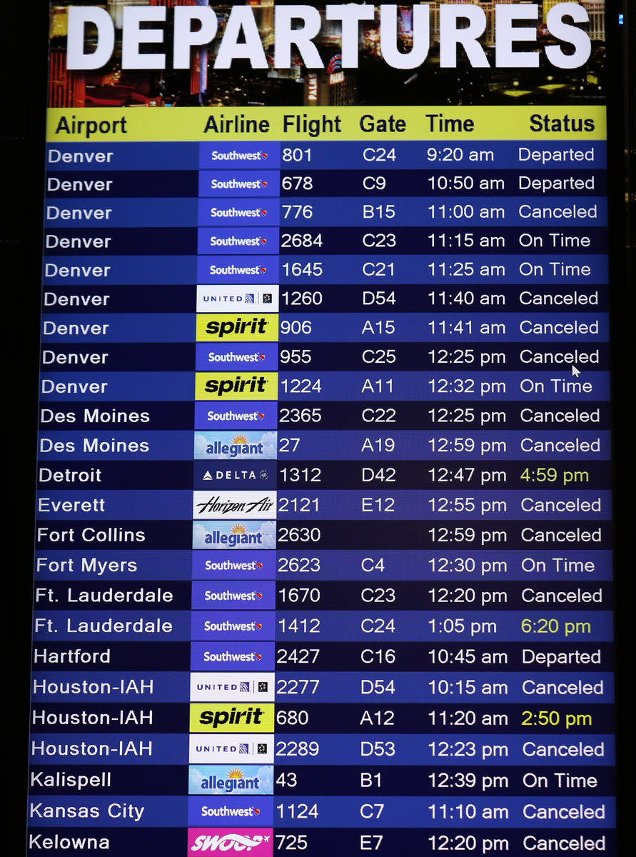 A flight departure information board displays several cancelled flights at Las Vegas McCarran I ...