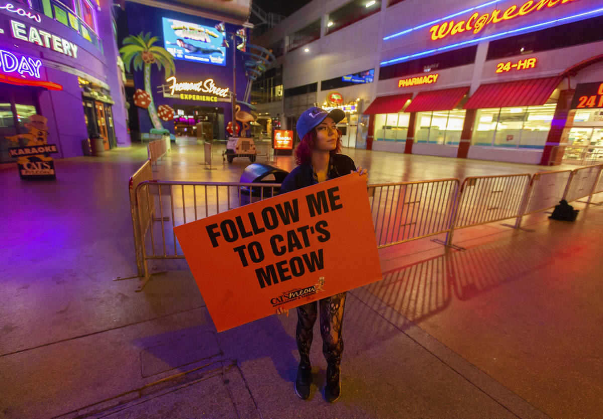 Kat V holds a sign advertising The Cat's Meow karaoke bar in downtown Las Vegas, where the stre ...