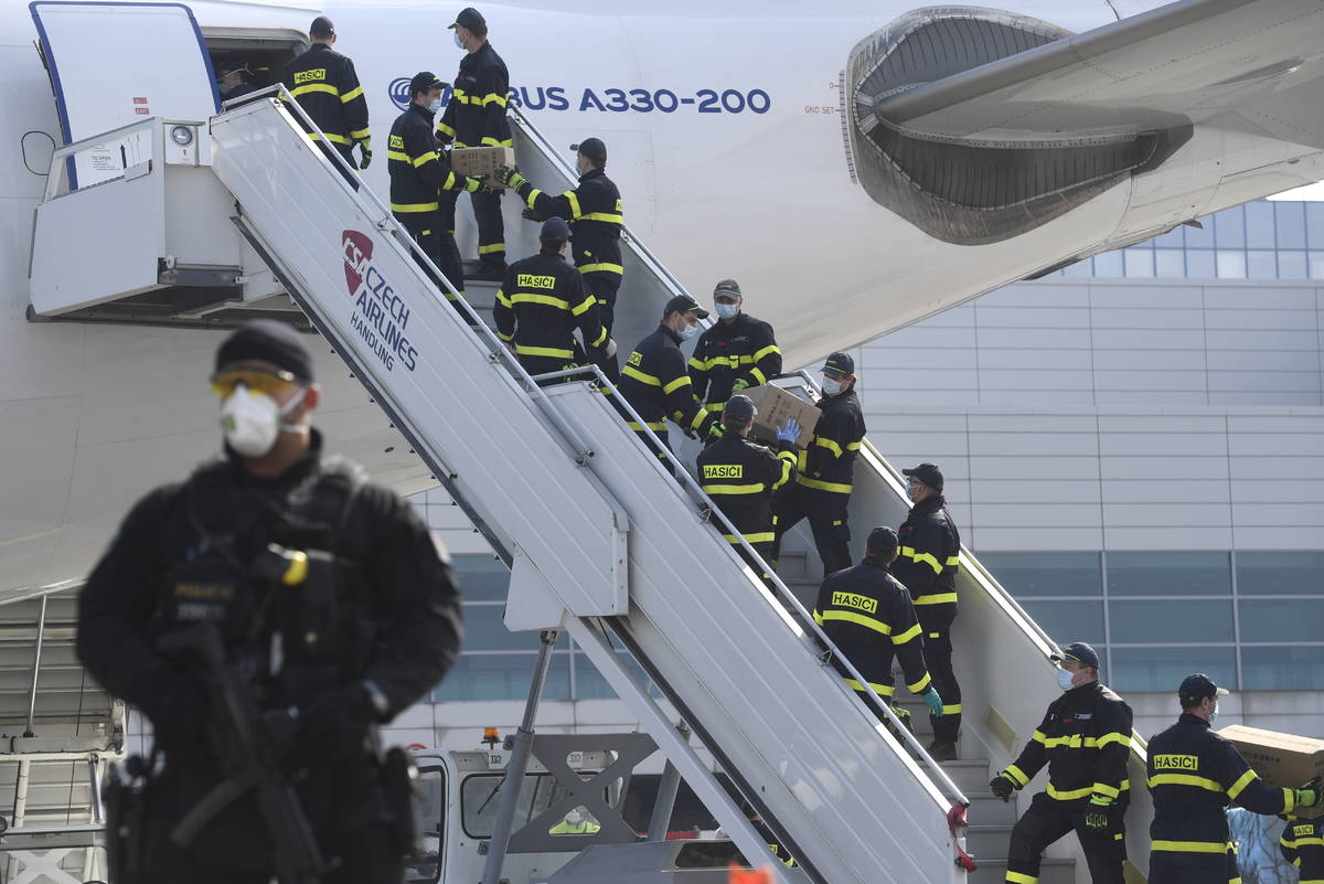 A police officer holds a gun as firefighters unload an airplane after its arrival at the Vaclav ...