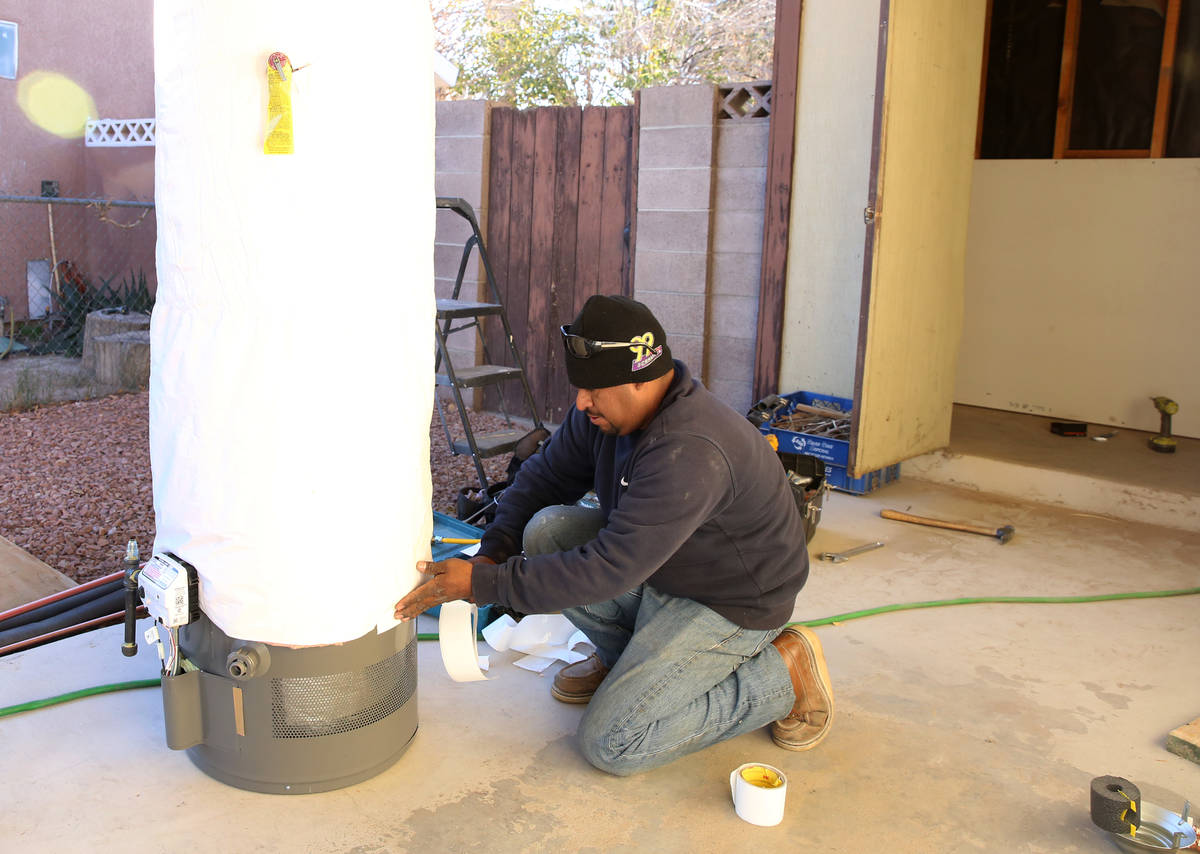 Abraham Gonzalez insulates a water heater outside a Las Vegas home in this Dec. 12, 2017, file ...