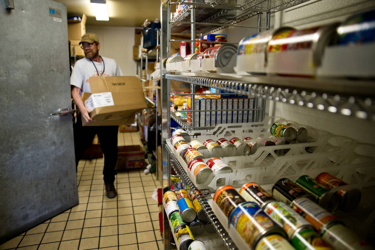 Scott Shepard carries a box of donated food into a large refrigerator at Casa de Luz community ...