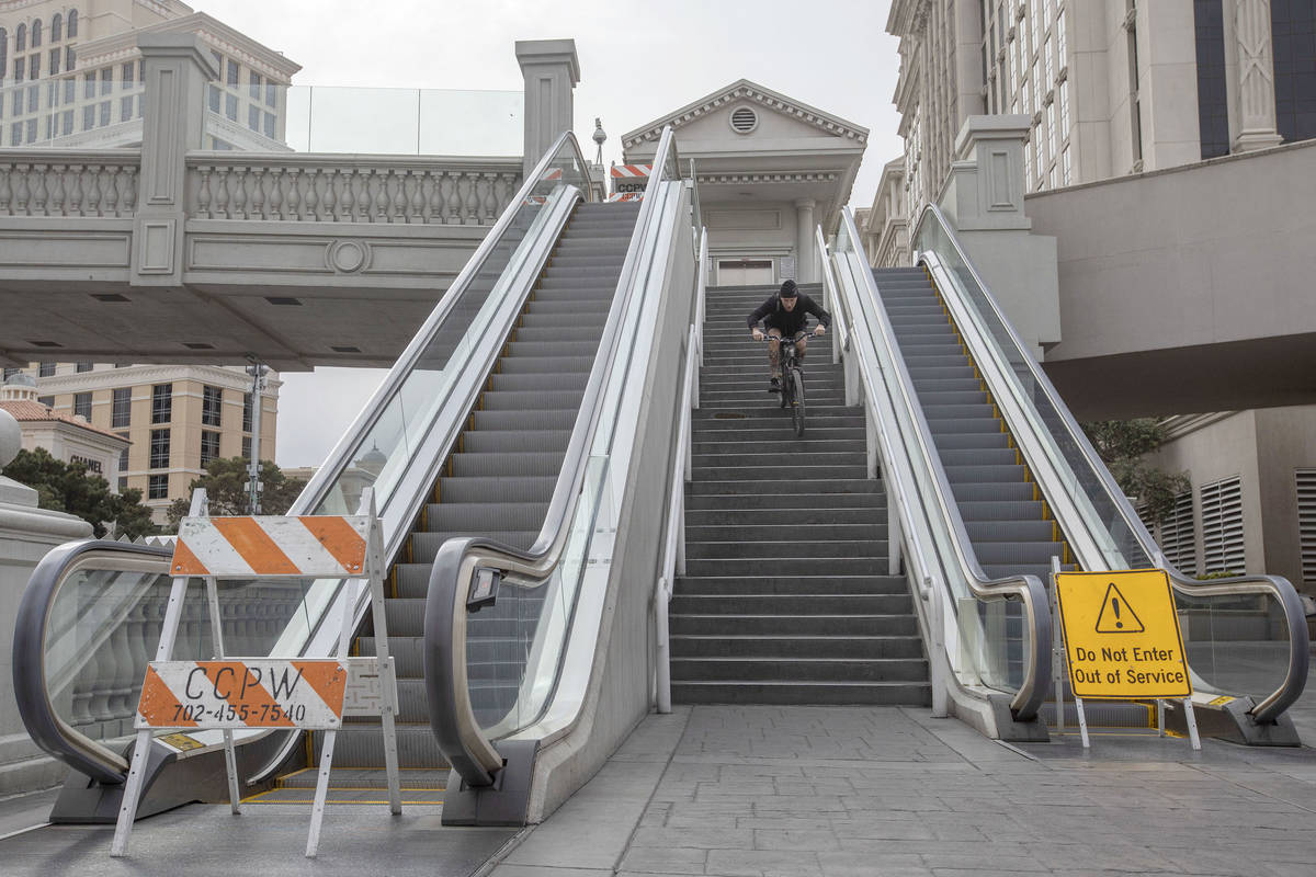 Las Vegan Matt Cremeans bikes down stairs of a pedestrian bridge on the Strip is empty on Wedne ...