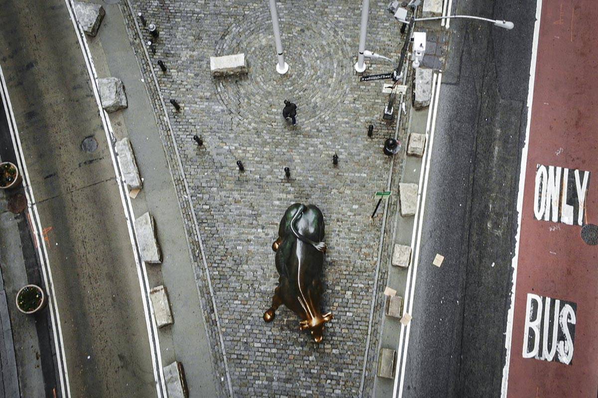A lone pedestrian walks down Broadway past the Charging Bull statue as COVID-19 concerns empty ...