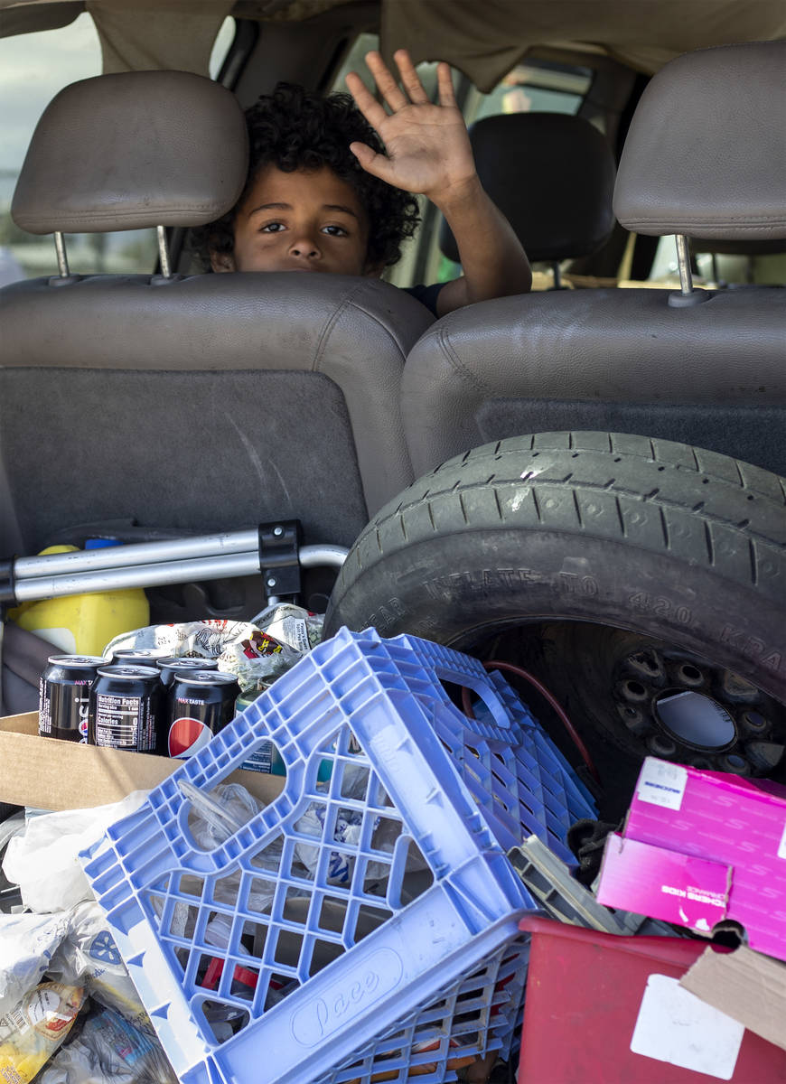 8-year-old Masen Flowers waves out of his mother's van as they drive through a food bank hosted ...