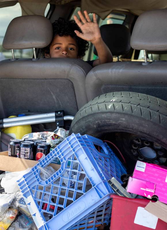 Eight-year-old Masen Flowers waves out of his mother's van as they drive through a food bank ho ...