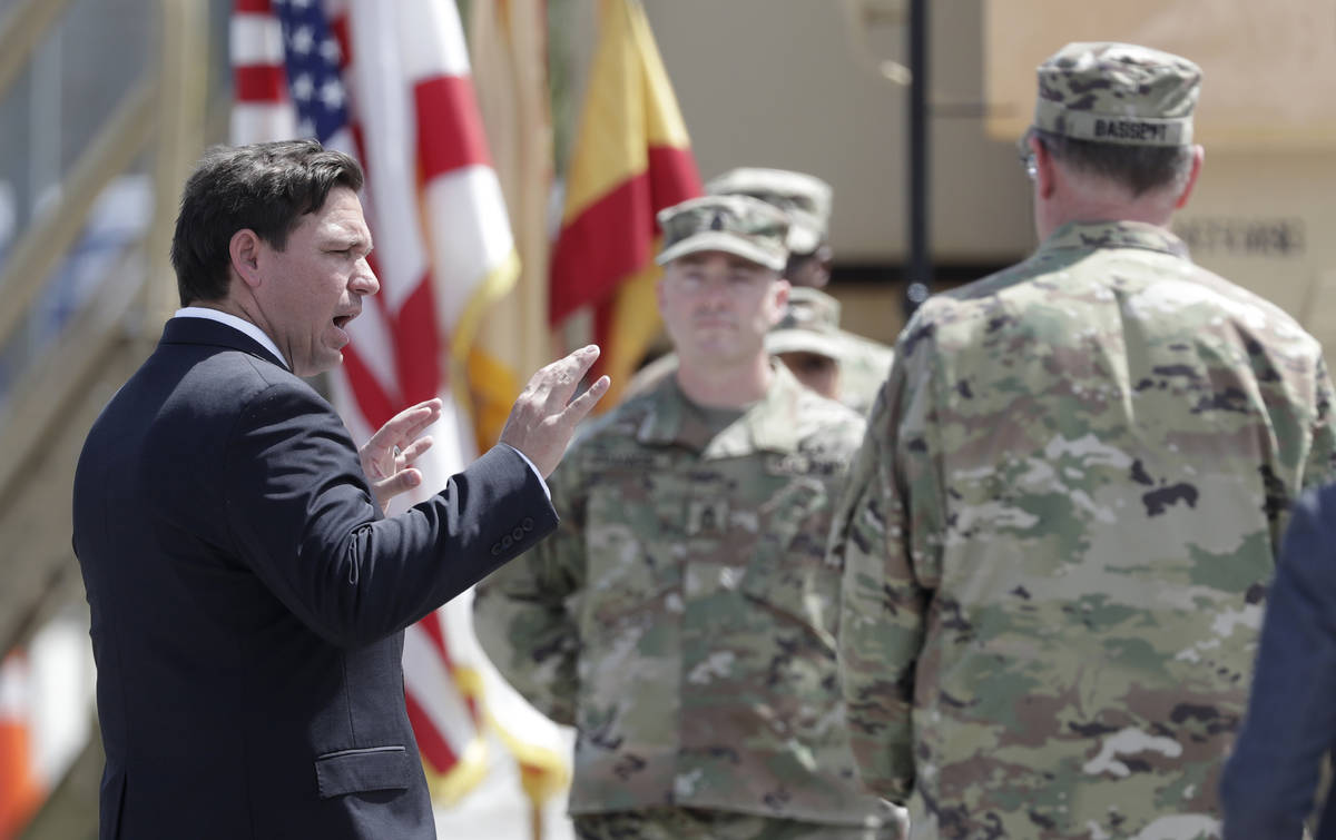 Florida Gov. Ron DeSantis, left, talks with members of the Florida National Guard, Sunday, Marc ...