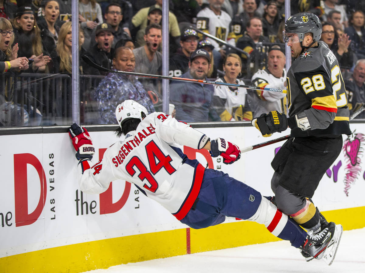 Washington Capitals defenseman Jonas Siegenthaler (34, left) is kicked to the ice after a shot ...