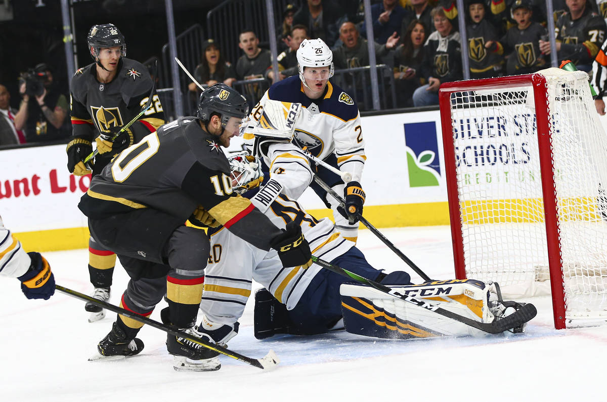 Golden Knights' Nic Roy (10) sends the puck past Buffalo Sabres goaltender Carter Hutton (40) t ...