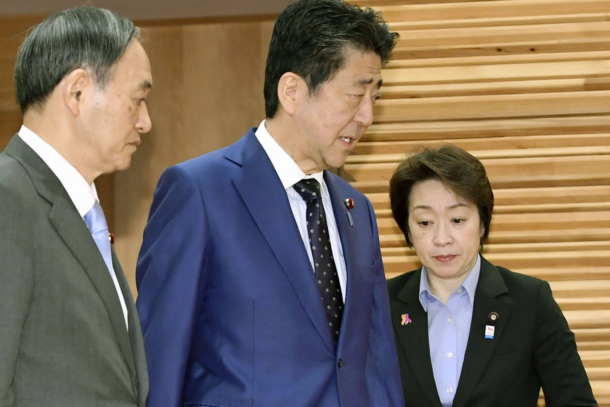 Japanese Prime Minister Shinzo Abe, center, walks past Olympic Minister Seiko Hashimoto, right, ...