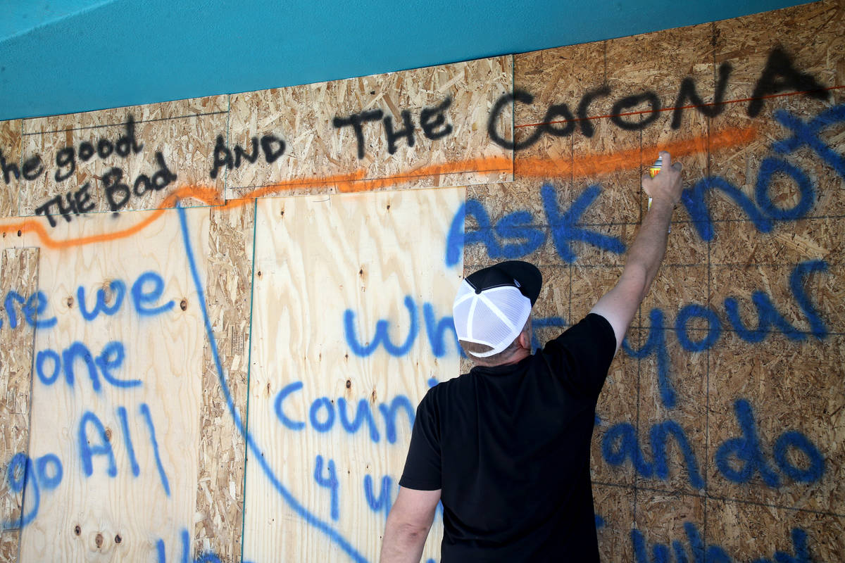 Jeff Anthony, owner of Vintage Vegas, paints on the boarded up windows of his store on Main Str ...