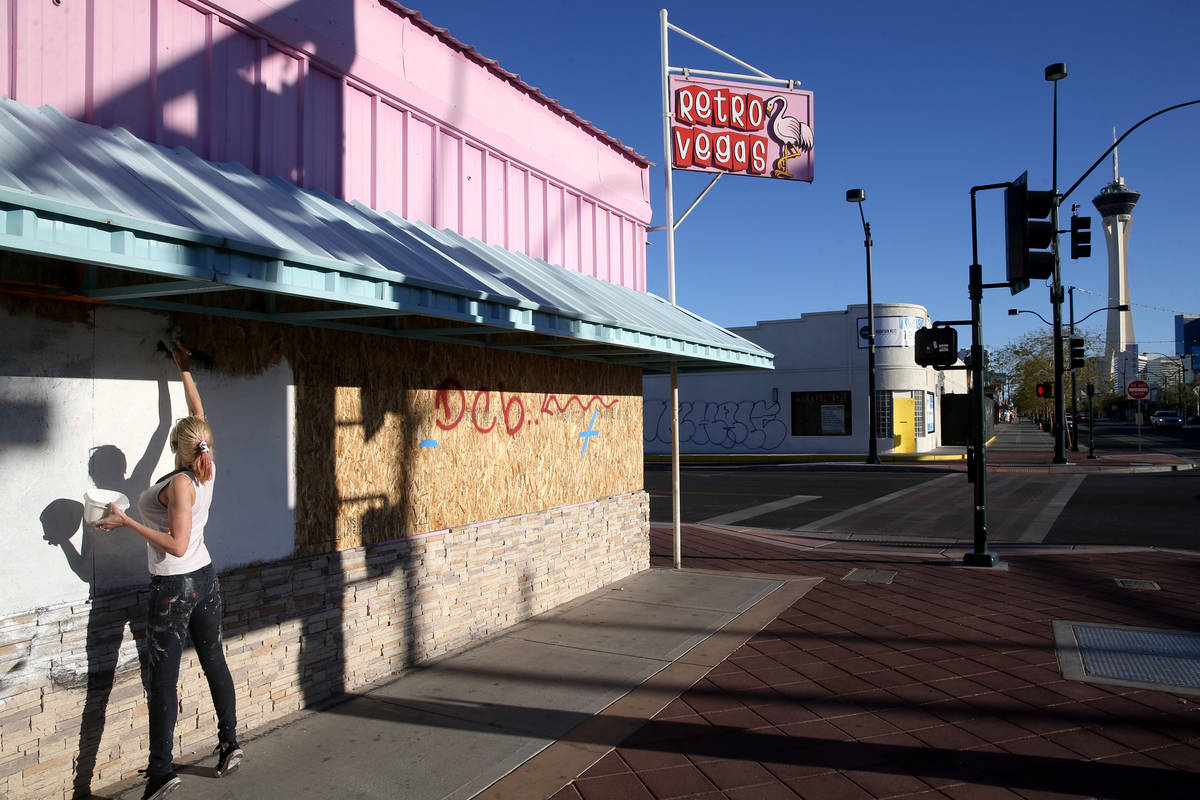 Artist Sheridee Hopper covers graffiti before painting a mural on the boarded up windows of Ret ...