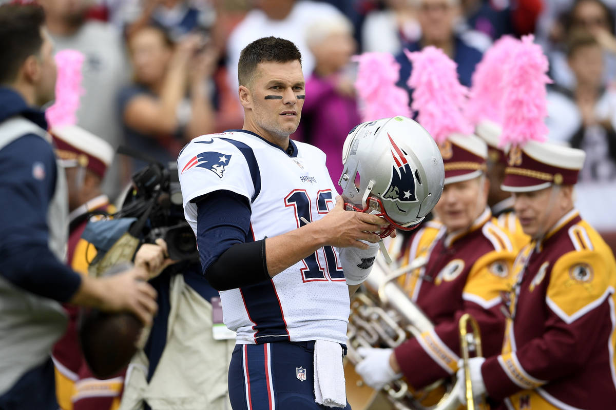 New England Patriots quarterback Tom Brady (12) puts on his helmet before an NFL football game ...
