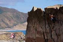 A climber climbs a rock formation along the Pacific Coast Highway, Monday, March 23, 2020, in M ...