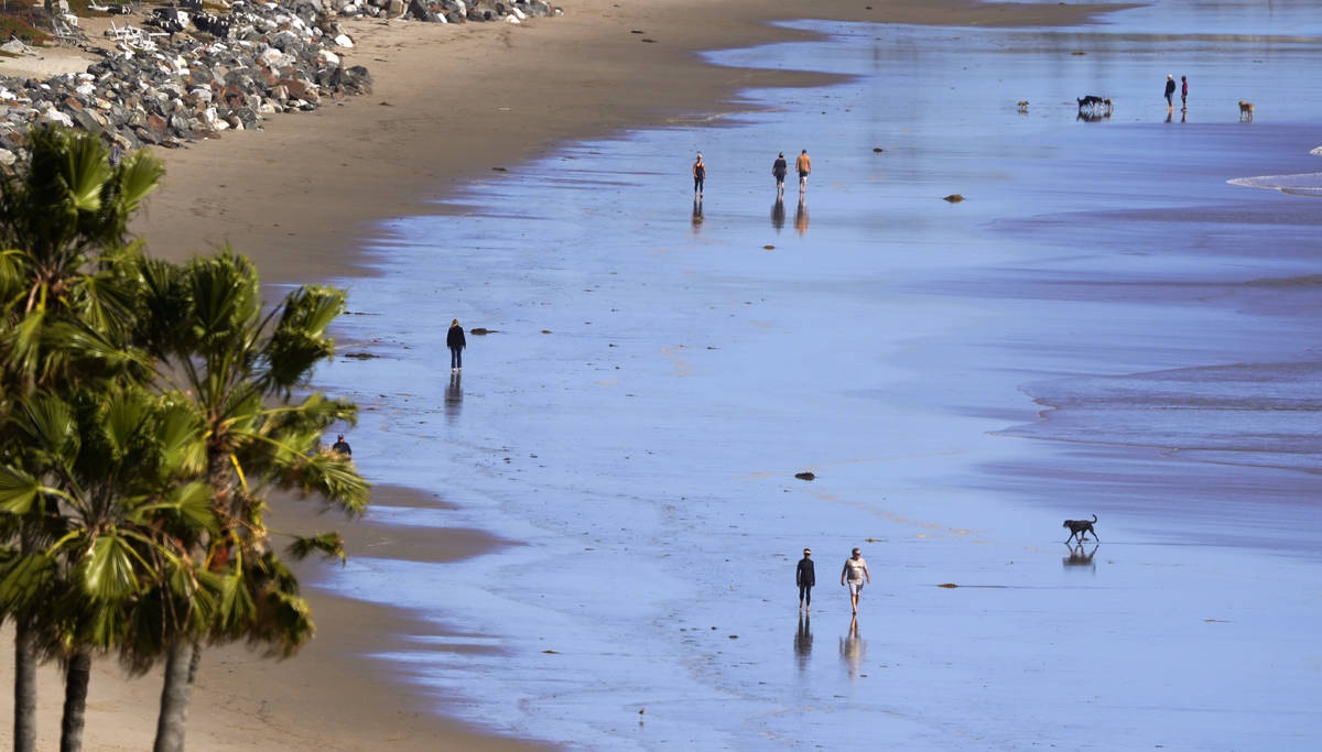 People walks along Zuma Beach, Monday, March 23, 2020, in Malibu, Calif. Officials are trying t ...