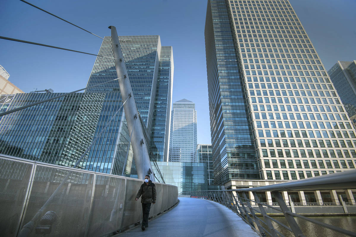 A man wearing a protective mask walks in Canary Wharf, during rush hour, in London, Wednesday M ...