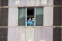 In a Wednesday, March 18, 2020, file photo, medical workers wearing face masks gesture from hos ...