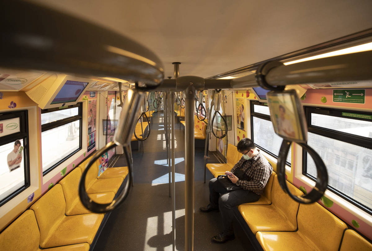 A commuter wears face mask to protect himself from new coronavirus at a skytrain in Bangkok, Th ...