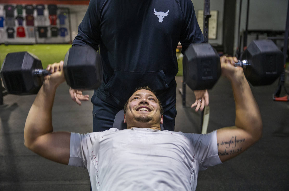 Las Vegas Raiders fullback Alec Ingold presses weights as trainer Brian Bott spots him at Sport ...