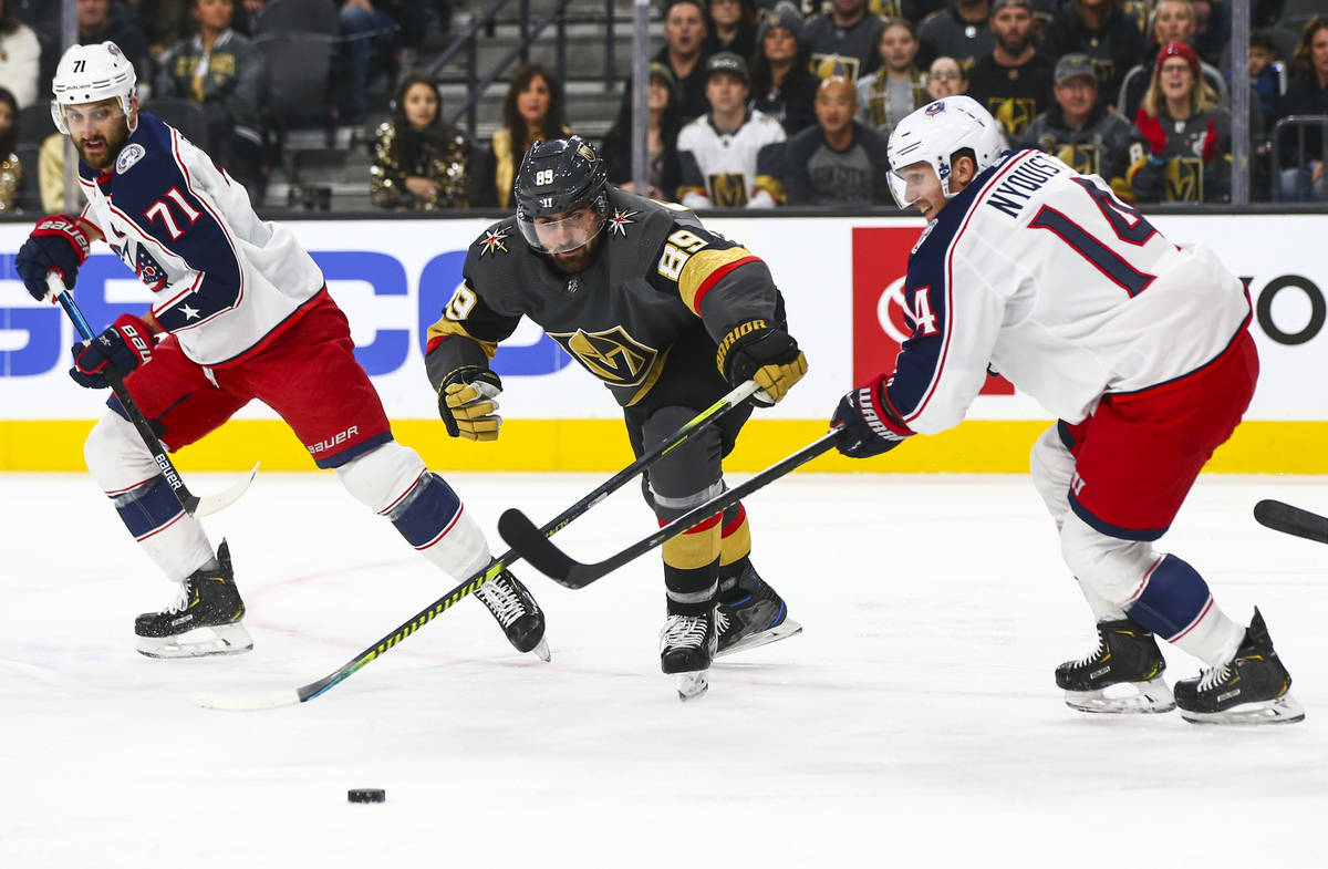 Golden Knights' Alex Tuch (89) chases after the puck between Columbus Blue Jackets' Nick Folign ...